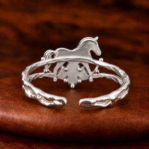 A sterling silver open cuff ring featuring a horse silhouette and small bead details, displayed on a dark brown wooden surface.